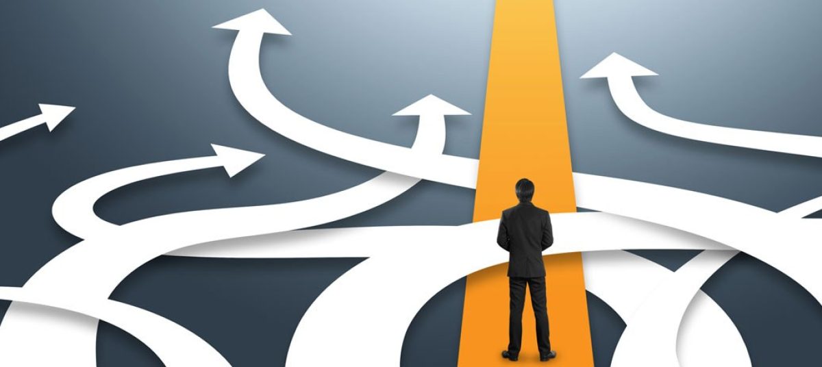 Uomo in giacca che osserva un percorso con molte frecce direzionali, simbolo delle scelte strategiche nella gestione del cambiamento aziendale.